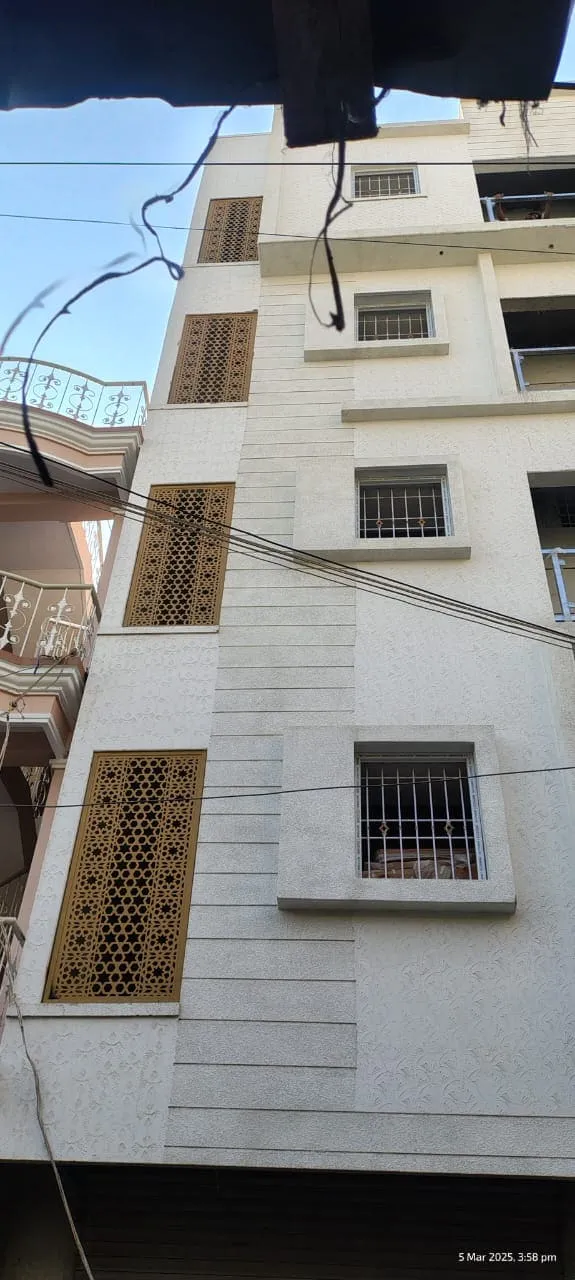 CNC laser cut gold finish decorative jali panels installed on a multi-storey residential building exterior facade in Bangalore