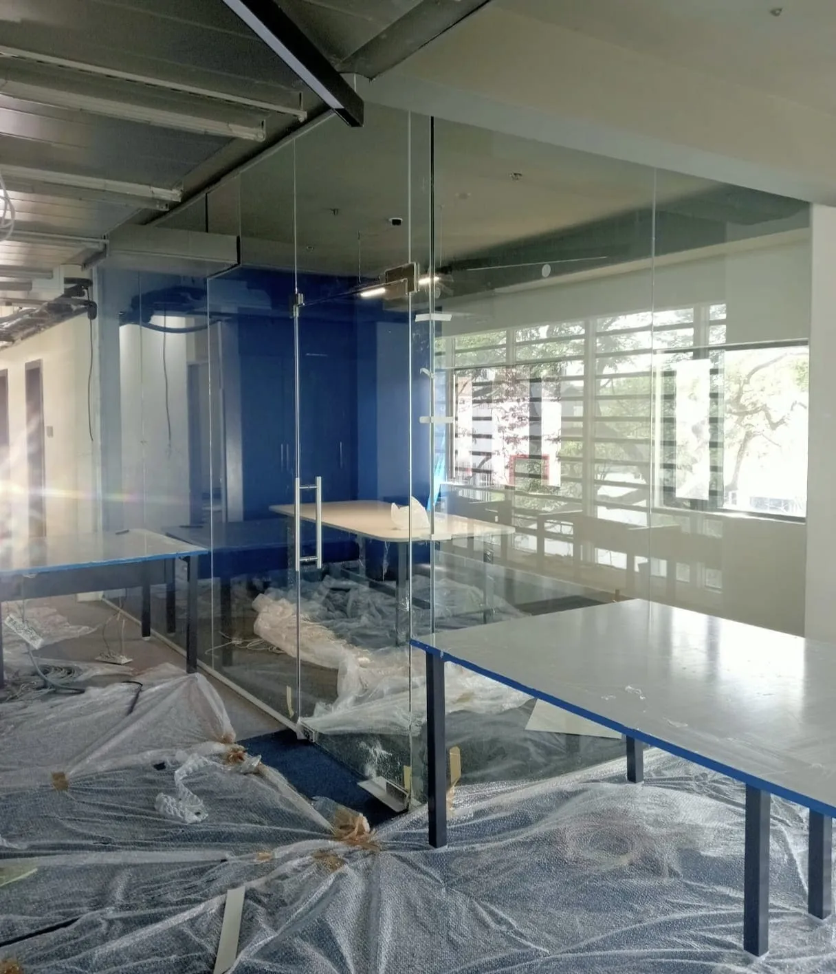 Frameless toughened glass partition and cabin door being installed in a corporate office in Bangalore