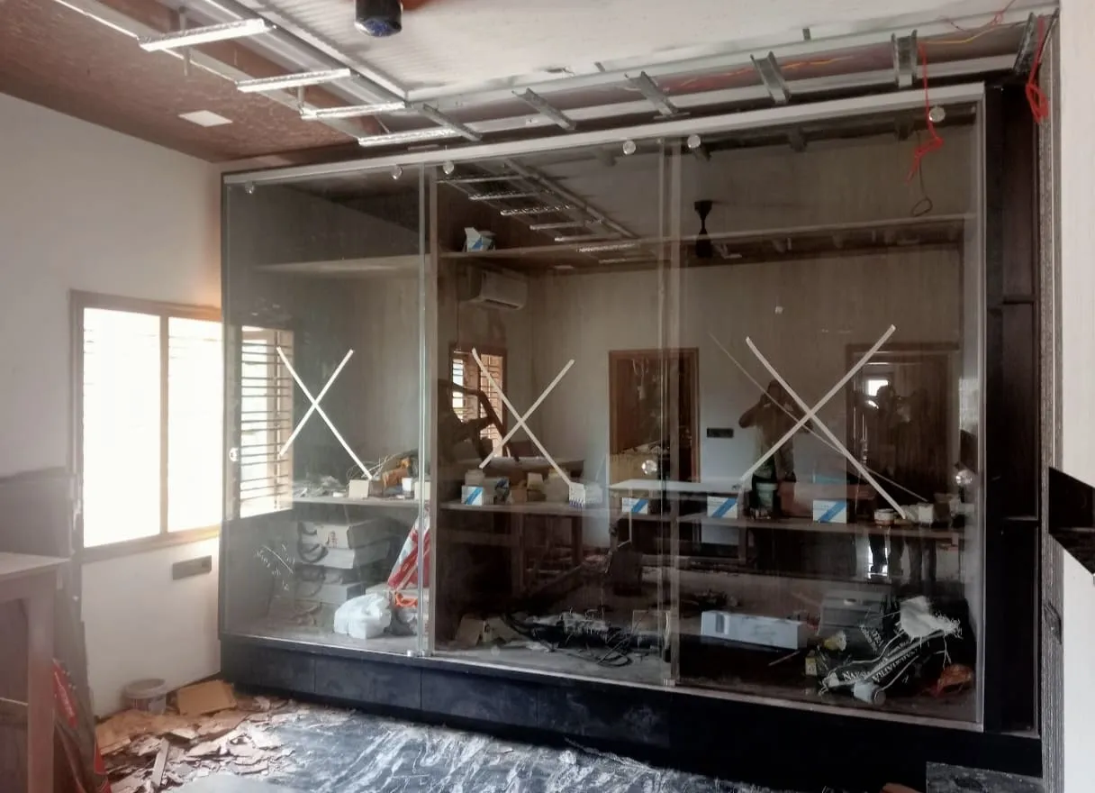 Frameless toughened glass sliding partition panels being installed for a commercial shop interior under construction in Bangalore
