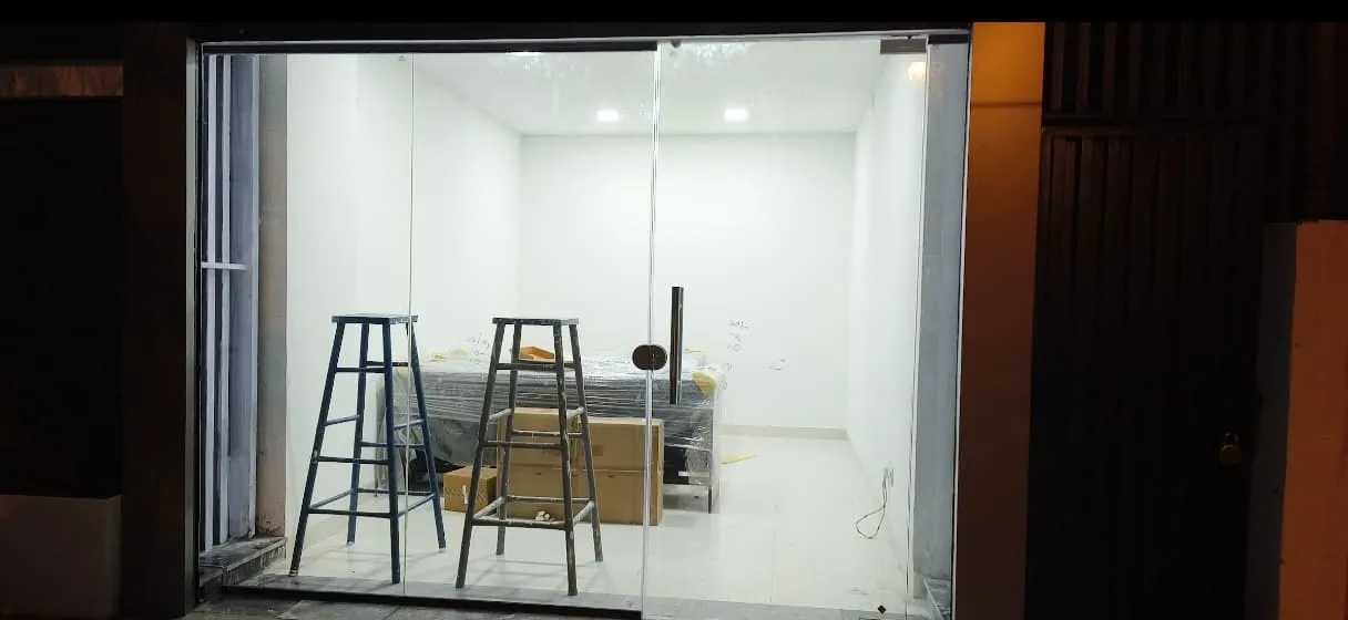 Newly installed frameless toughened glass shop front with bright white interior lighting at night in Bangalore ready for interior fit-out