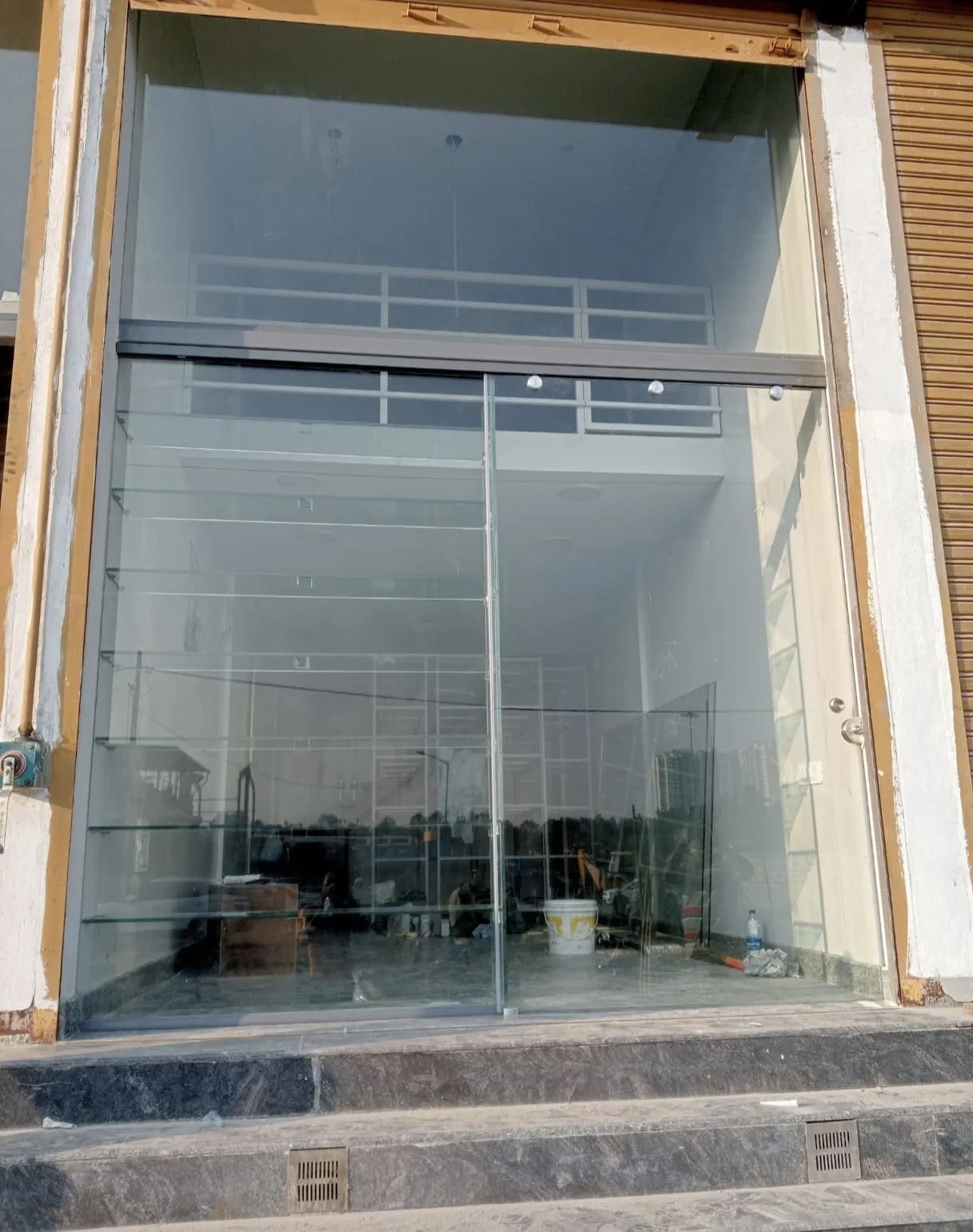 Frameless toughened glass sliding door installed at a commercial storefront in Bangalore