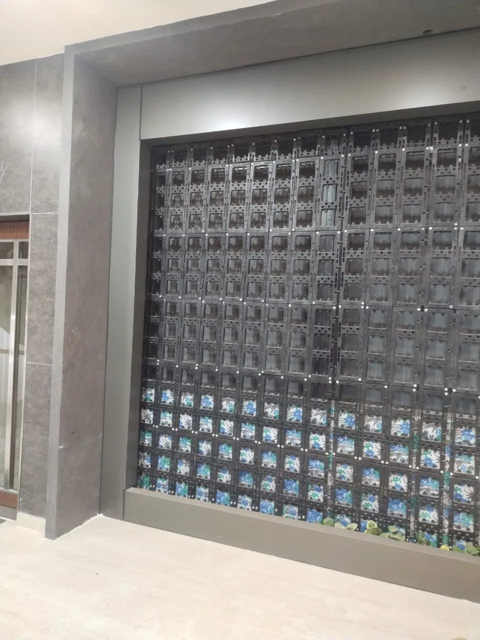 Interior modular green wall system featuring black plastic planter grids with variegated plants at the base.