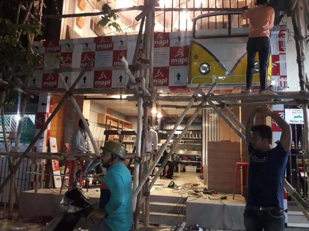 Workers on bamboo scaffolding installing ACP ceiling panels during restaurant interior fit-out construction in Bangalore
