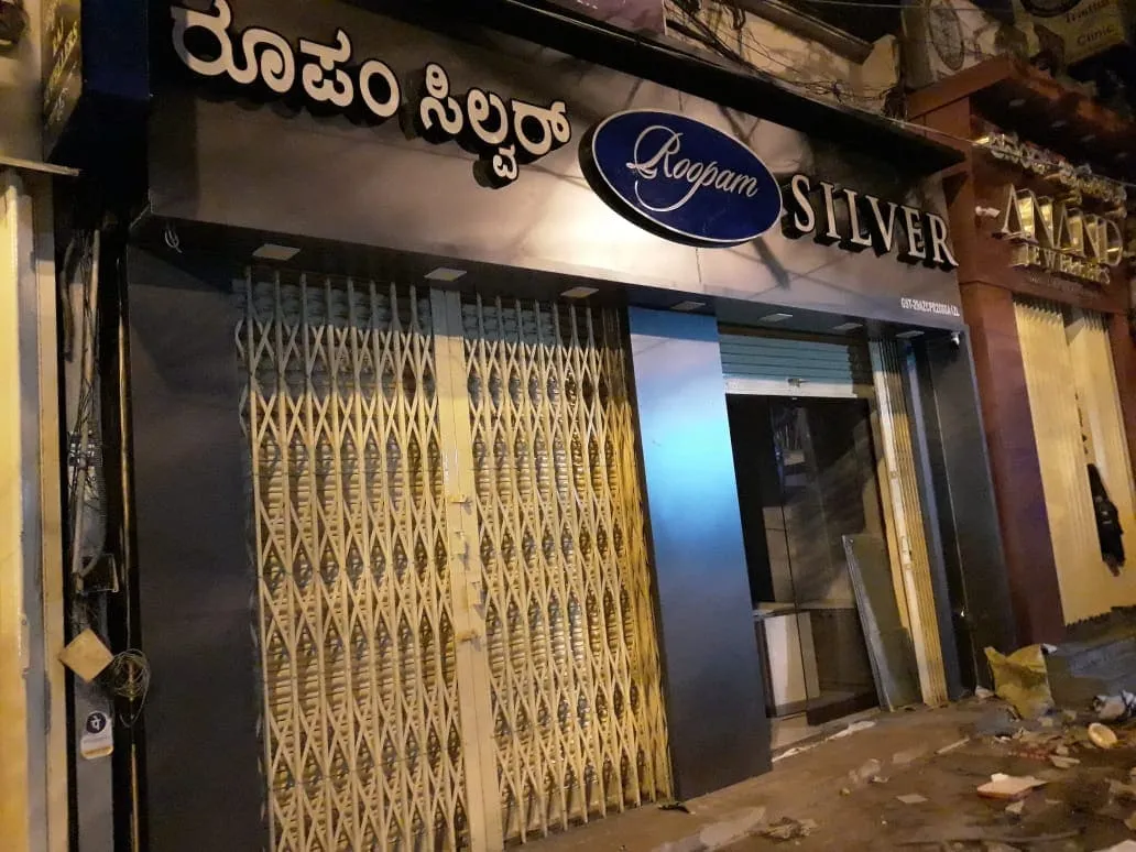 Roopam Silver jewellery store ACP cladding fascia and illuminated signage at night in Bangalore with collapsible shutter closed
