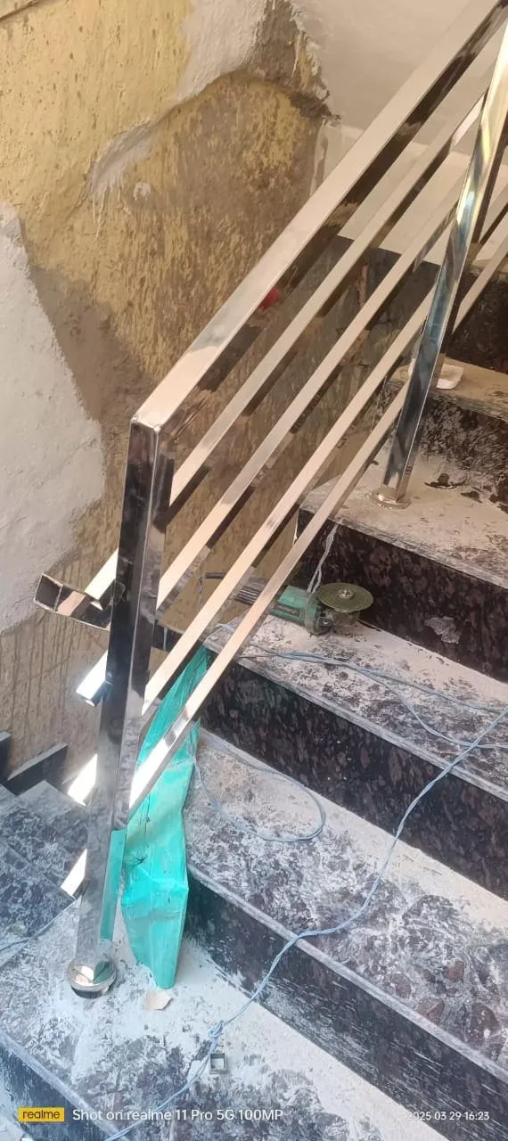 Polished stainless steel horizontal bar staircase railing being installed on marble steps in Bangalore